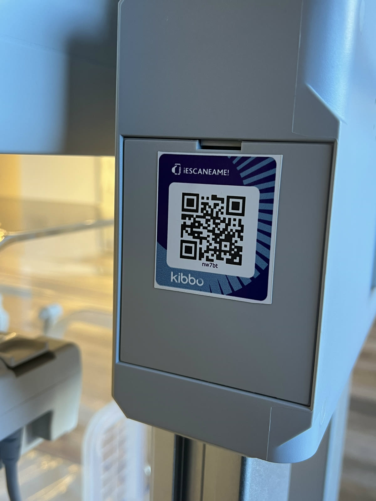 Foto de un sticker con código QR de KIBBO pegado sobre un equipo médico en el piso del hospital.